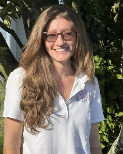 Jennifer Garrison, with glasses, smiling outdoors in a white Mrs. Marvelous Cleaning polo.