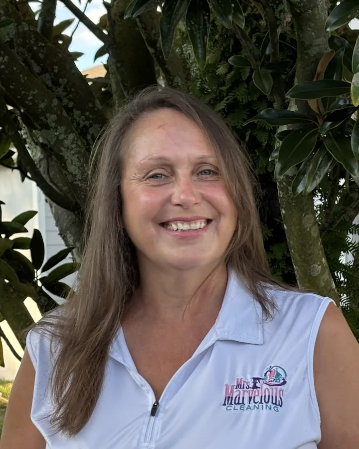 Michelle Martin smiling outdoors in a white sleeveless polo with the Mrs. Marvelous Cleaning logo.